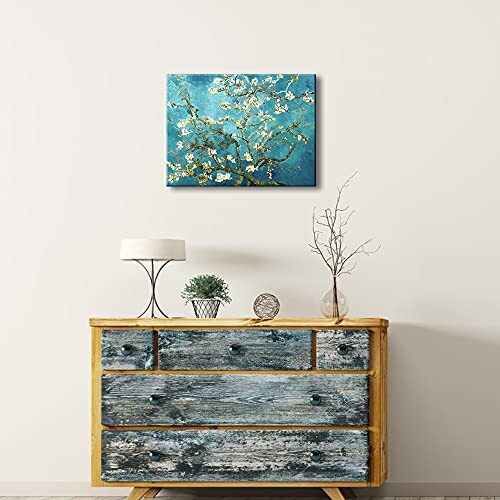 Rustic wooden dresser with decor and wall art featuring branches on a teal background